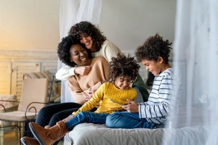 Same-sex female couple with their two children looking at an ipad