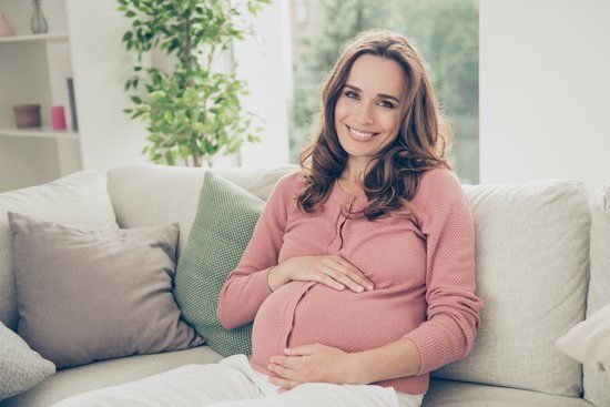 Lady in pink jumper pregnant holding her bump