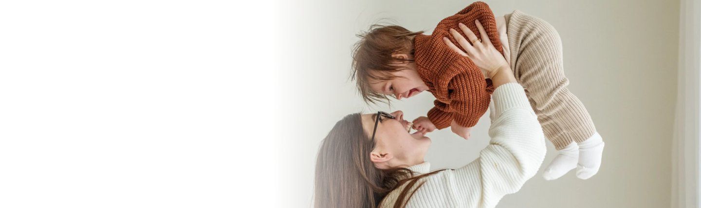 Parent holding their baby in the air playing together - induction of uvulation page for manchester fertility