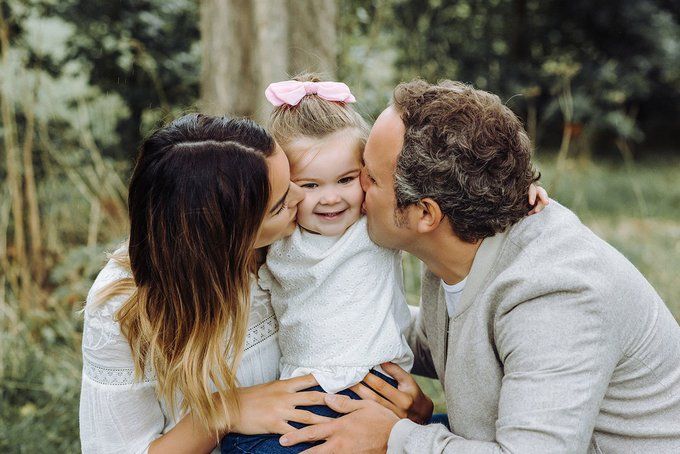 Couple with baby kissing on the cheeks