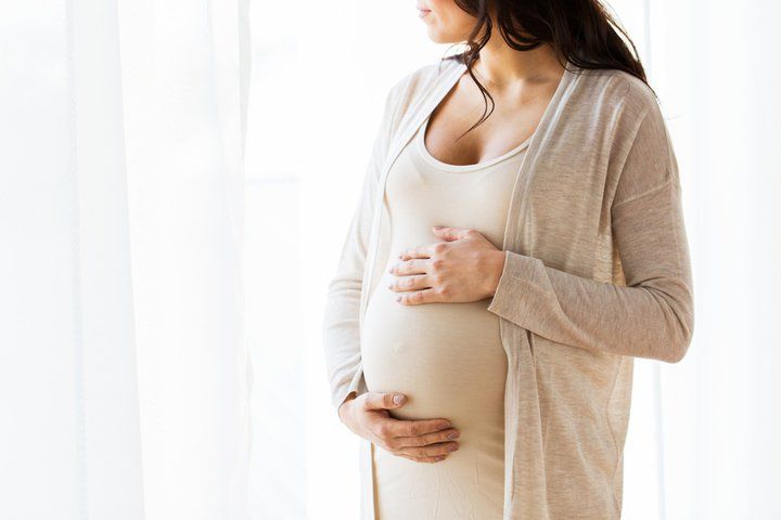 pregnant woman holding her bump in long dress