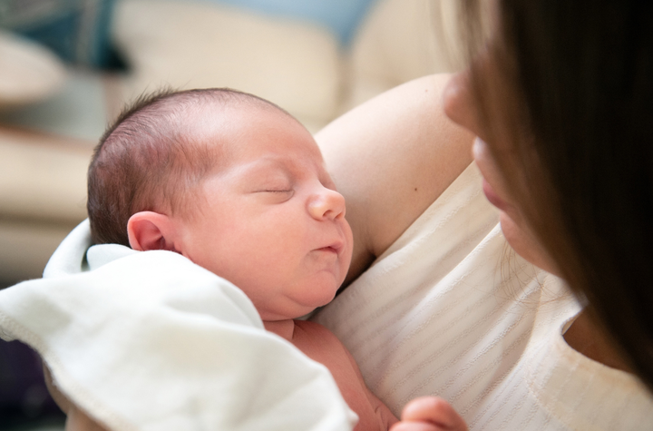 Baby with big blue eyes leaning on his hand