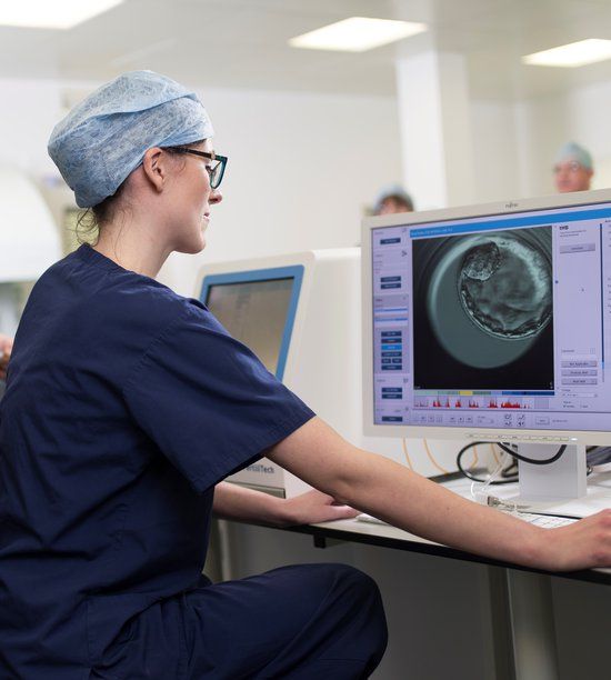 Specialist embryologist using an EmbryoScope incubator and iDAScore AI software to examine a time-lapse video of an embryo