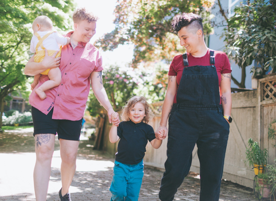 LGBT family holding hands walking down a path